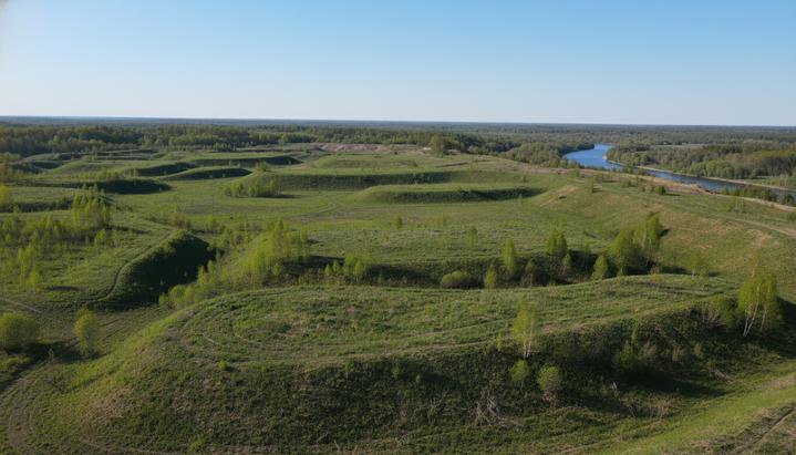 США отменяют 14 регуляторных актов для поддержки угольной промышленности Рекультивированный угольный карьер с зелеными холмами и молодой растительностью на месте бывшей горной выработки.