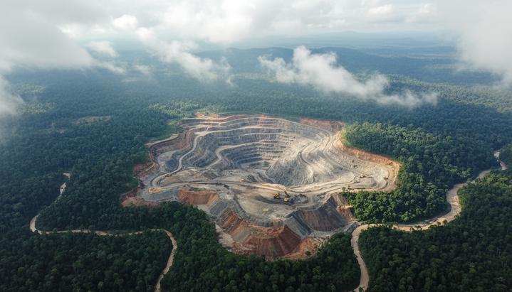 Огромный угольный карьер, расположенный вплотную к густому тропическому лесу в Индонезии, вид с воздуха.
